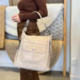 Cartera negra de símil cuero con doble cierre superior, bolsillo frontal con tapa y broche magnético, bolsillos laterales con cierre y correa larga regulable y desmontable.