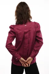 Camisa blanca de lino con corte clásico, cuello camisero, mangas largas con puños abotonados y volados en los hombros.