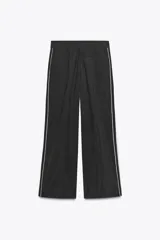 Pantalón negro de tiro alto con cintura elástica, bolsillos delanteros y detalle de banda lateral blanca.