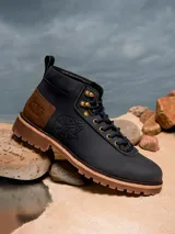 Botines de cuero color azul marino con detalles en marrón y suela marrón. Presenta el logo del Halcón Milenario en el lateral y el logo de Star Wars en el talón.