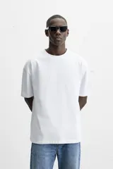 Camiseta blanca de algodón compacto, corte relaxed fit, cuello redondo y mangas cortas.
