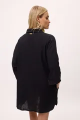 Vestido camisero a rayas verticales de colores pastel, con cuello camisero, cierre frontal con botones y mangas largas.