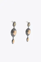 Aros colgantes metálicos plateados con tres dijes circulares con textura y apliques de joya, abalorios y piezas labradas combinadas a contraste. Cierre con tuerca.