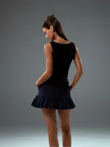 Minifalda de jean azul oscuro con cintura alta, cierre con doble botón y falda plisada.
