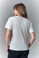 Remera negra de algodón con cuello redondo y mangas cortas. Presenta un estampado en el escote que simula un collar estilo boho con cuentas, borlas y dijes.