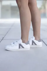 Sneakers blancas con cierre de velcro y diseño minimalista en gris.