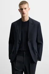 Blazer azul marino de corte recto, con cuello de solapa de muesca, cierre frontal con dos botones, bolsillos de solapa en la cadera y aberturas en la espalda. Confeccionado en tejido de algodón con elasticidad y sin forro interior.
