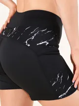 Calza corta deportiva negra, tipo biker, con cintura alta y un panel lateral con estampado de mármol blanco.