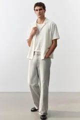 Camisa de manga corta color crema, de punto texturizado de mezcla de algodón de peso medio. Modelo con cuello abierto, tapeta lisa y bajo recto.