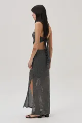 Vestido tejido calado plateado, con escote halter, cut outs en el abdomen y falda larga con tajo lateral.