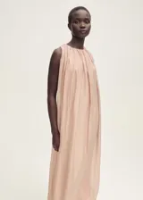 Vestido largo color rosa pálido, sin mangas, con cuello redondo fruncido y falda evasé. Confeccionado en tejido mezcla lyocell con bajo abullonado y cierre de botón en el cuello.