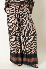 Pantalón palazzo de rayón y viscosa con estampado de cebra en tonos beige y negro. Presenta cintura elastizada, bolsillos laterales y corte amplio.