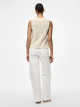 Top tejido color crema, con cuello redondo y sin mangas.