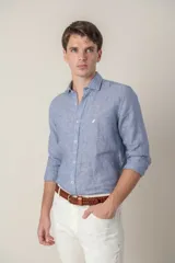 Camisa de manga larga, color azul, confeccionada en lino, con cuello tipo short collar y un pequeño pájaro bordado en amarillo en el pecho.