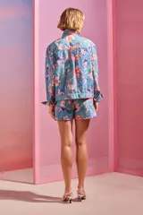 Chaqueta de denim celeste con estampado floral tropical y apliques bordados en pedrería.