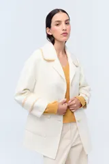 Tapado de lana color blanco, con cuello grande y detalles decorativos en los puños.