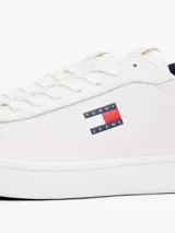 Zapatillas de estilo tenis confeccionadas en piel napa blanca, con diseño de corte bajo y cierre de cordones. Presentan un panel de contraste en el talón en color azul marino, forro de poliéster y suela de goma. Incluyen el parche distintivo de Tommy Jeans en el lateral.