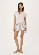 Pijama de dos piezas compuesto por una remera de manga corta color rosa pálido con un pequeño texto estampado y un short a rayas verticales en tonos beige y gris oscuro.