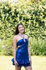 Vestido corto negro con escote en V, breteles finos cruzados en la espalda, abertura en la cintura y falda con volados.