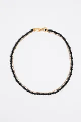 Collar doble, uno con perlitas negras y otro con cadena dorada.