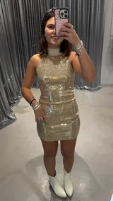 Vestido dorado de lentejuelas, corto y al cuerpo, con cuello halter.