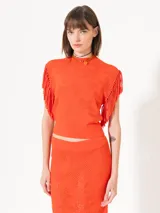 Top color naranja tejido con calados, sin mangas y con flecos en las sisas.