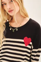 Sweater de punto a rayas horizontales en blanco y negro, con detalle de corazón rojo en el pecho.