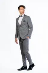 Traje de hombre de dos piezas color azul vibrante, compuesto por saco de un solo botón con solapas de pico en negro y pantalón a juego. Se complementa con camisa blanca, moño azul y pañuelo de bolsillo negro.