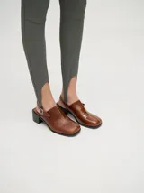 Mocasines color beige con taco bloque de madera color negro y correa trasera ajustable.