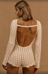 Conjunto de short y top de tejido crochet color crudo, con mangas largas y detalle de cinturón de cadena plateada.