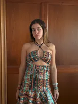 Vestido corto con estampado de rayas horizontales en tonos grises y negros. Diseño con escote halter que se ata al cuello, abertura central en el busto y falda corta con volado.