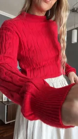 Sweater rojo de tejido de punto trenzado con cuello alto y mangas largas.