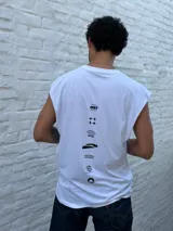 Musculosa blanca de corte amplio, con hombros caídos y cuello redondo. Presenta un estampado minimalista en negro en el pecho con la palabra "OSTEN" y un símbolo abstracto.