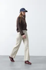 Pantalón negro de tiro alto, corte recto y silueta clásica. Presenta costuras verticales marcadas en la parte delantera de las piernas.