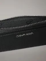 Tarjetero verde con textura croco, cuenta con 4 ranuras para tarjetas y un bolsillo monedero con cremallera, con el logo de Calvin Klein.