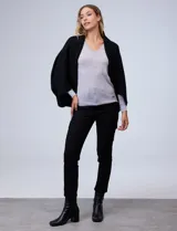 Cardigan negro de tejido suave, estilo poncho o capa, con cuello tipo chal y mangas amplias.