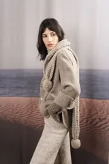 Bufanda tejida a mano en punto arroz color beige, con pompones en los extremos.