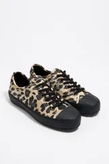 Zapatillas deportivas bajas con estampado animal print, puntera y suela de goma negra y cordones negros.