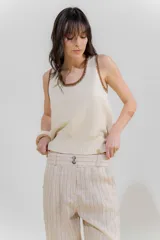 Musculosa de punto color crudo con cuello y sisas ribeteadas en marrón.