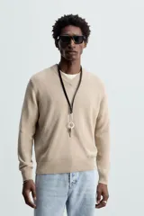 Jersey de punto color beige, con cuello en V y mangas largas.
