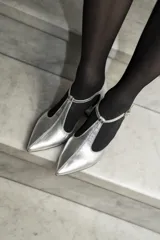 Sandalia de cuero color bordó, con acabado charolado, punta fina y tacón cuadrado de 5 cm. Presenta una tira en forma de T sobre el empeine y una correa con hebilla alrededor del tobillo.