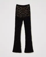 Pantalón acampanado negro confeccionado en algodón tejido a crochet con estampado floral, bordes festoneados, cintura elástica y forro corto en contraste.