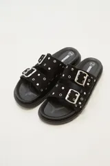 Sandalia tipo birkenstock de color negro, con dos tiras ajustables con hebillas metálicas plateadas. Las tiras están decoradas con tachas plateadas.
