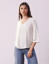 Blusa color blanco con escote en V y aplique de crochet.