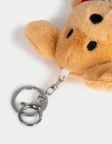 Llavero de peluche con forma de perro color beige, vestido con un sweater rojo y un collar de perlas.