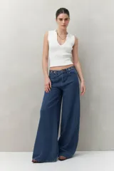 Pantalón de jean negro de corte ultra wide, tiro medio y detalles metálicos en la cintura.