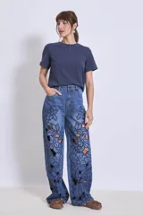 Pantalón de jean azul con bordados florales y aberturas en forma de flor en las piernas.