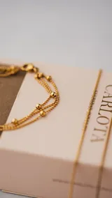 Pulsera dorada de acero quirúrgico con triple cadena y cuentas.