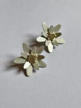 Par de aros plateados con forma de flor y centro dorado con textura.