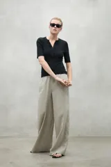 Pantalón de lino color beige, de pierna ancha, cintura elástica y bolsillos laterales.